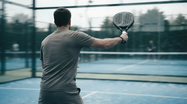 A padel player hitting a controlled forehand, seen from behind